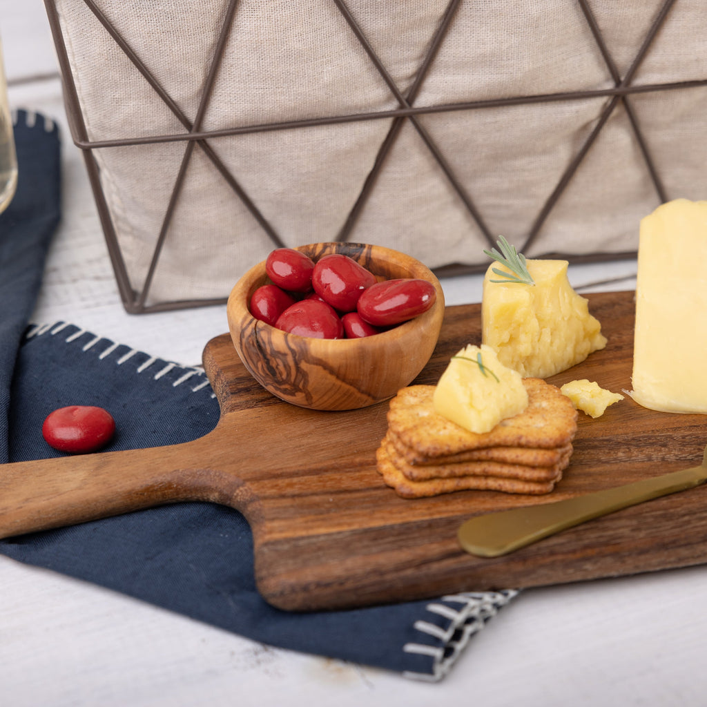 Small wooden bowl of chocolate covered cherries with honey wheat crackers and cheese