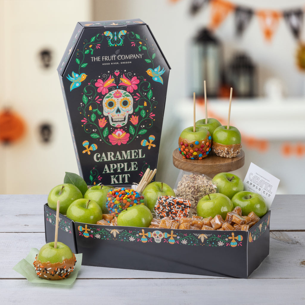Recipe card for the Caramel Apple Kit A person holding the Caramel Apple Kit  Apple, candies, and caramels in a festive box Coffin shaped caramel apple kit for dia de muertos Caramel apples with M&M's and nuts M&M's and green apples in a festive box Caramels, candies, and green apples in a festive box Bags of candy in the Dia de Muertos box Openned transparent bag of M&M's